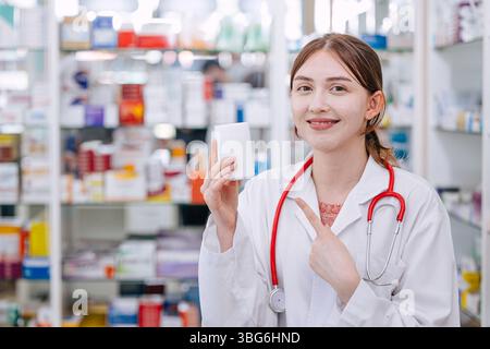 Felice dottore farmacista in farmacia mano che tiene puntando a medicina pillole scatola per raccomandare buona medicina sorridendo Foto Stock