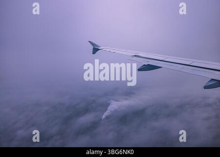 Aeroplano che vola sopra il cielo nuvole nebbiose tempestose , vista dalla finestra dell'aereo delle turbine ad ala e dell'orizzonte Foto Stock