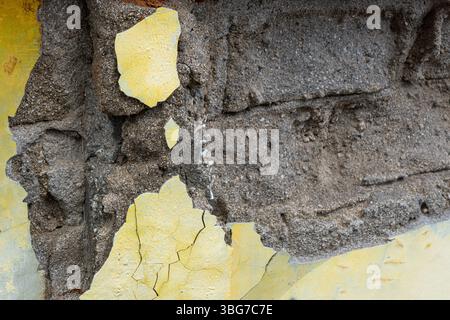 Muro con un foro e una vernice gialla e bianca. Il muro è fatto di mattoni Foto Stock