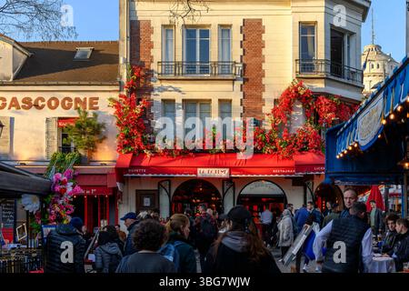 Persone che guardano in cima a Montmartre intorno a Place du Tertre. Con i turisti che bevono o mangiano all'aperto, godendosi la vita parigina. Foto Stock