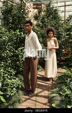 Una giovane coppia gode di una romantica passeggiata attraverso una splendida serra circondata da piante lussureggianti. Foto Stock