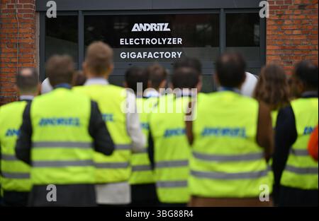 Erfurt, Germania. 4 giugno 2025. Gli ospiti dell'inaugurazione di un centro di competenza sull'elettrolisi di Andritz Schuler GmbH indossano giubbotti di sicurezza. Un impianto all'avanguardia per l'assemblaggio di pile di elettrolizzatori è stato costruito nel sito industriale di Erfurt, vecchio di oltre 100 anni. Gli elettrolizzatori sono di importanza cruciale per la produzione di idrogeno verde. Crediti: Martin Schutt/dpa/Alamy Live News Foto Stock