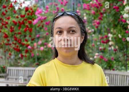 Ritratto di una donna in un parco estivo tra splendidi fiori Foto Stock