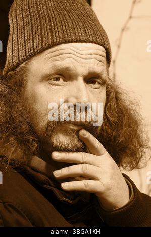 Ritratto della testa e delle spalle di un uomo anziano con barba folta e cappellino in lana monocromatico Foto Stock