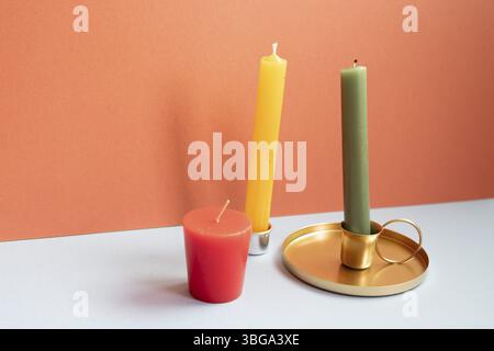 Candela sul tavolo grigio. sfondo rosso della parete Foto Stock