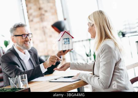 Partner commerciali che discutono di transazioni immobiliari in un ambiente di ufficio collaborativo Foto Stock