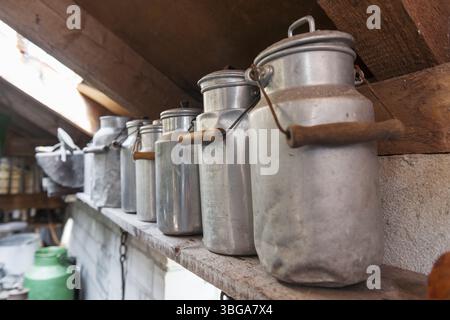 Il vecchio latte di alluminio si getta su un ripiano sotto il tetto Foto Stock