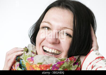 Ritratto testa e spalle di una donna dai capelli neri di mezza età su uno sfondo bianco con una sciarpa colorata e fiorita, che ride in un uomo amichevole Foto Stock