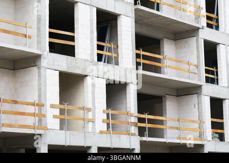 Costruzione in calcestruzzo. Facciata grigia senza finitura con finestre. Moderna struttura residenziale in corso. Investimenti immobiliari urbani. Foto Stock