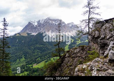 Vista sulle montagne di Zugspitze con foresta alpina e primo piano roccioso in Tirolo Foto Stock