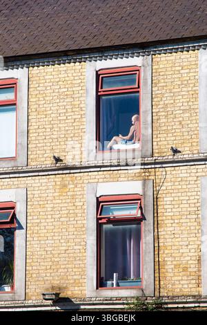 Un uomo si siede, da solo, a guardare fuori da una finestra di sopra. Cambridge, Inghilterra, Regno Unito. Concetti: Solitudine, isolamento Foto Stock