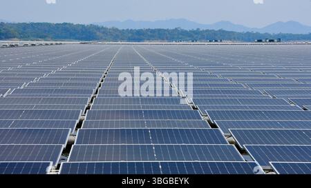 Una vasta gamma di pannelli solari galleggianti installati su un serbatoio d'acqua con colline boscose e montagne sullo sfondo. rendering 3d. Foto Stock