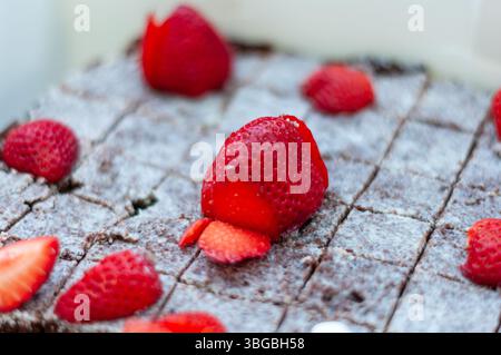 Un dessert con fragole sopra. Le fragole vengono tagliate a metà e disposte su una torta al cioccolato Foto Stock