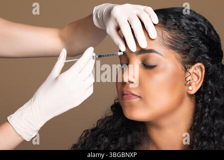 Cosmetologist making botox injection in interbrow zone to latin chubby woman getting anti-wrinke treatment, closeup Foto Stock