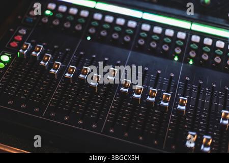 Primo piano di una consolle di mixaggio con manopole e fader illuminati, che evidenziano la precisione e il controllo nella produzione audio professionale Foto Stock