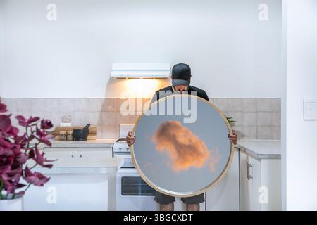 Uomo con specchio magico in cucina Foto Stock