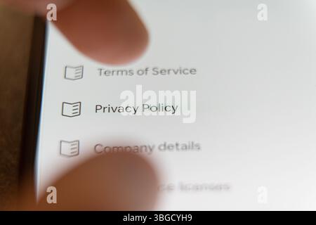 Primo piano dello schermo di uno smartphone con un dito per toccare l'opzione Informativa sulla privacy in un menu delle impostazioni. Foto di alta qualità Foto Stock