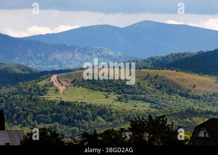 Village panorama with forested layers and a white church dome shining through trees Foto Stock