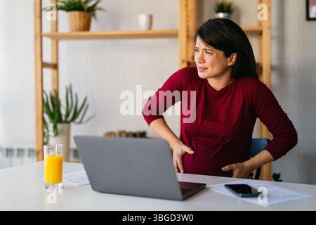 Donna incinta con dolori addominali e alla schiena, contrazioni nell'ultimo trimestre di gravidanza Foto Stock
