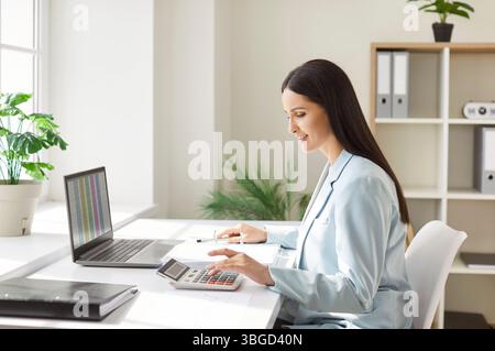Donna che lavora in contabilità con notebook in ufficio Foto Stock