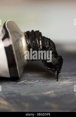 primo piano della vernice nera che strizza dal tubo Foto Stock