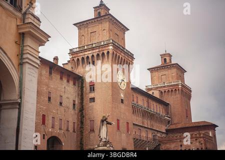 Ferrara, 2 gennaio 2025: Castello estense con torre dell'orologio e statua di girolamo savonarola, frate domenicano, sotto il cielo nuvoloso a ferrara Foto Stock