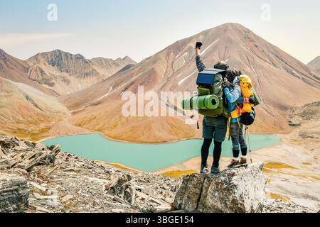 Due escursionisti adulti caucasici insieme si stagliano sulla cima della montagna e ammirano il panorama. Uomo e donna in piedi e abbracciati sulla cima della montagna Foto Stock