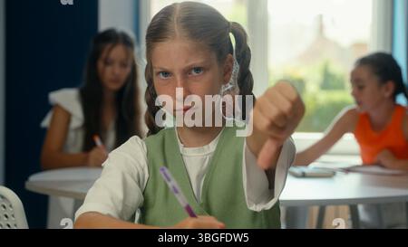 Adolescente caucasica scontenta triste rancore offeso scolaretta scolaretta allieva insoddisfatta lezione di istruzione primaria studio di classe cattivo dito Foto Stock