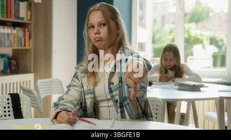 Ragazza caucasica triste offeso teenager allieva studentessa figlia bambino bambino istruzione primaria compito di lezione cattivo antipatia dito giù Foto Stock