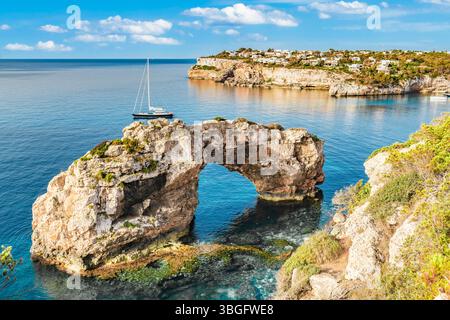 Paesaggio costiero roccioso mediterraneo con uno yacht a vela ancorato la mattina presto - 2275 Foto Stock
