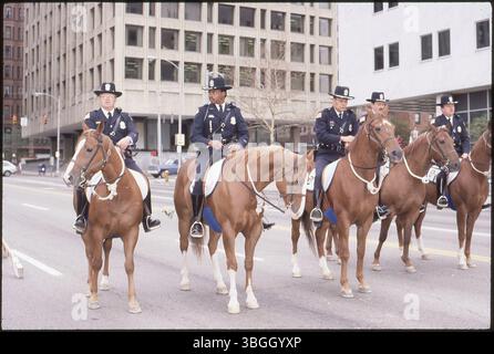 Cinque agenti di polizia a cavallo marciano in una parata lungo West Broad e Front Street. L'Huntington Plaza e gli edifici del Dipartimento dell'istruzione sono visibili sullo sfondo. Foto Stock