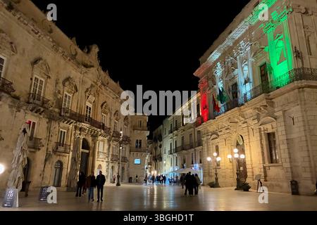 Palazzo Beneventano del Bosco e Palazzo del Vermexio illuminati con bandiera italiana di notte, Siracusa, Sicilia Foto Stock