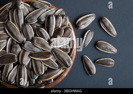 Semi di girasole neri in una ciotola, su sfondo nero Foto Stock
