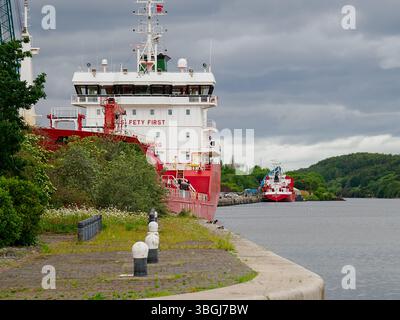 Ellesmere Port, Cheshire, UK,05-31-2025: Navi da carico rosse attraccate lungo un tranquillo canale sotto cieli nuvolosi. Foto Stock