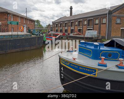 Ellesmere Port, Cheshire, Regno Unito, 05-31-2025: Museo nazionale dei corsi d'acqua. Barche storiche attraccate lungo un canale britannico con edifici in mattoni rossi nelle vicinanze. Foto Stock