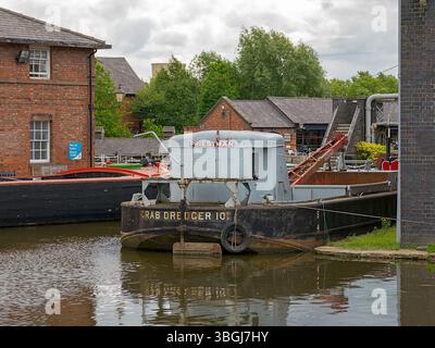 Ellesmere Port, Cheshire, Regno Unito, 05-31-2025: Museo nazionale dei corsi d'acqua. Storica draga di granchi ormeggiata in un pittoresco molo sul canale tra edifici industriali. Foto Stock