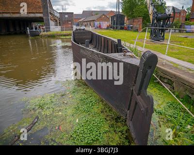 Ellesmere Port, Cheshire, Regno Unito, 05-31-2025: Museo nazionale dei corsi d'acqua. Storica barca in legno ormeggiata da un canale con vegetazione lussureggiante. Foto Stock