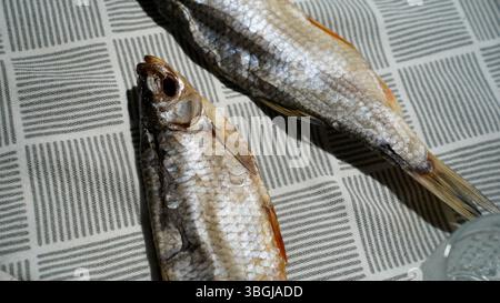 Pesce essiccato su tovaglia a motivi: Spuntino tradizionale dell'Europa orientale Foto Stock