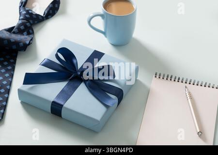 Happy Fathers Day. Biglietto d'auguri con omaggio, taccuino con rilegatura a molla su sfondo blu. Set classico creativo con tazza da caffè papà, cravatta. Acc. Uomini Foto Stock