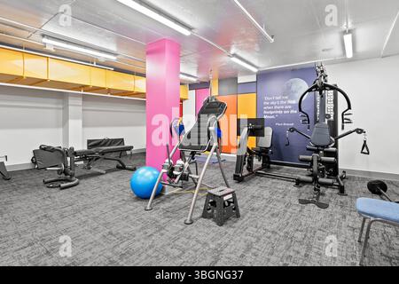 Palestra con una parete rosa e una palla blu. La palestra è piena di attrezzature sportive e una citazione sulla parete Foto Stock