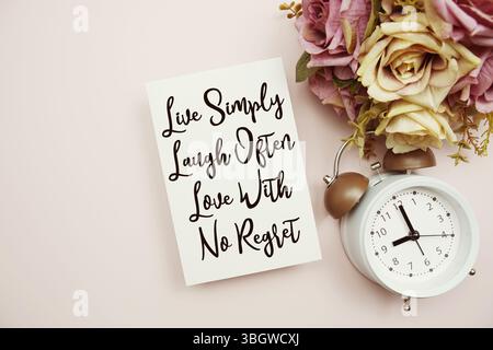 Live Simply Laugh often Love with No Remember testo su carta con sveglia su sfondo rosa Foto Stock