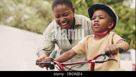 Sostegno, insegnamento e ragazzo in bicicletta con mamma per strada del quartiere per lo sviluppo dei bambini. Donna africana, sorriso o ragazzo nero con fiducia, aiuto o.. Foto Stock