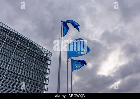 Tre bandiere europee sventolano drammaticamente contro un cielo buio e tempestoso Foto Stock