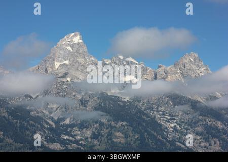 Una vista mozzafiato delle montagne del Grand Teton rivela vette frastagliate che emergono da un mare di nuvole. Il cielo è cristallino, mettendo in risalto l'essere naturale Foto Stock
