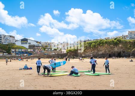 Un gruppo di principianti di surf che si preparano per una lezione di surf con un istruttore della scuola di surf SSS a Towan Beach a Newquay in Cor Foto Stock