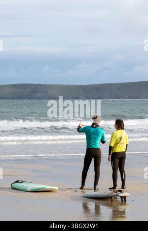 Un istruttore di surf che spiega la tecnica a un principiante a Towan Beach a Newquay in Cornovaglia nel Regno Unito. Foto Stock