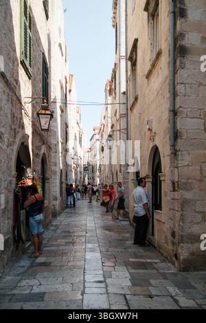Stretta strada pedonale nella città vecchia di Dubrovnik. Diminuendo la vista prospettica del vicolo affollato della città medievale nel pomeriggio. Foto Stock