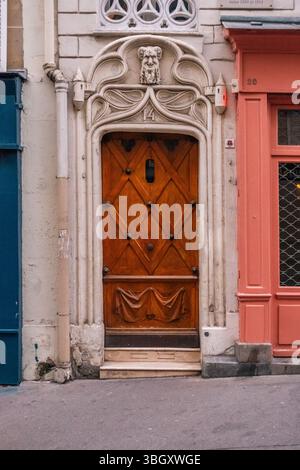 Una porta unica in legno fortemente intagliato con un motivo a diamante e borchie in metallo, collocata all'interno di un telaio in pietra ornato. Il telaio include un anim scolpito Foto Stock