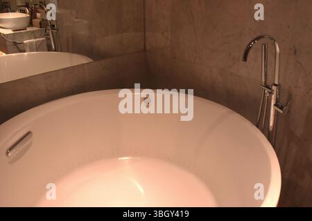 grande vasca da bagno bianca e riflesso sullo specchio in bagno Foto Stock