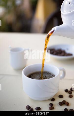 Caffè americano con chicchi di caffè in tazza bianca Foto Stock